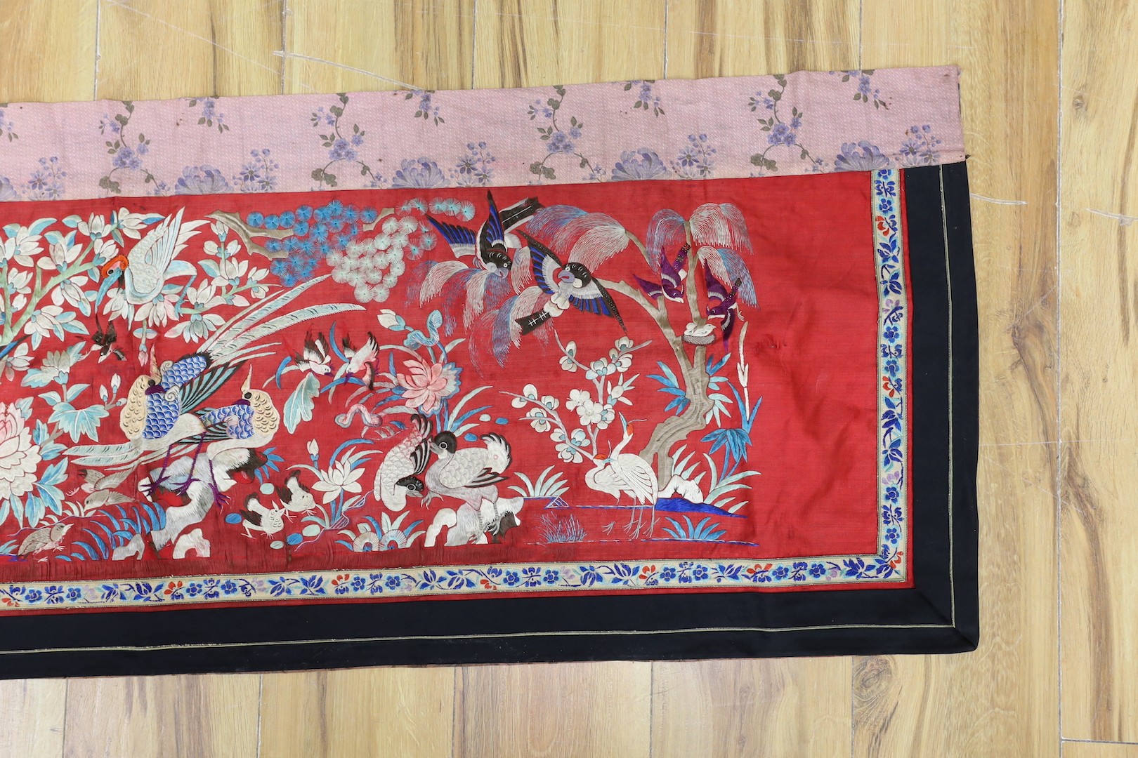 An early 20th century Chinese embroidered silk helmet multi coloured embroidery on a red background depicting oriental birds. 183cm x 47.5cm. 183cm x 47.5cm